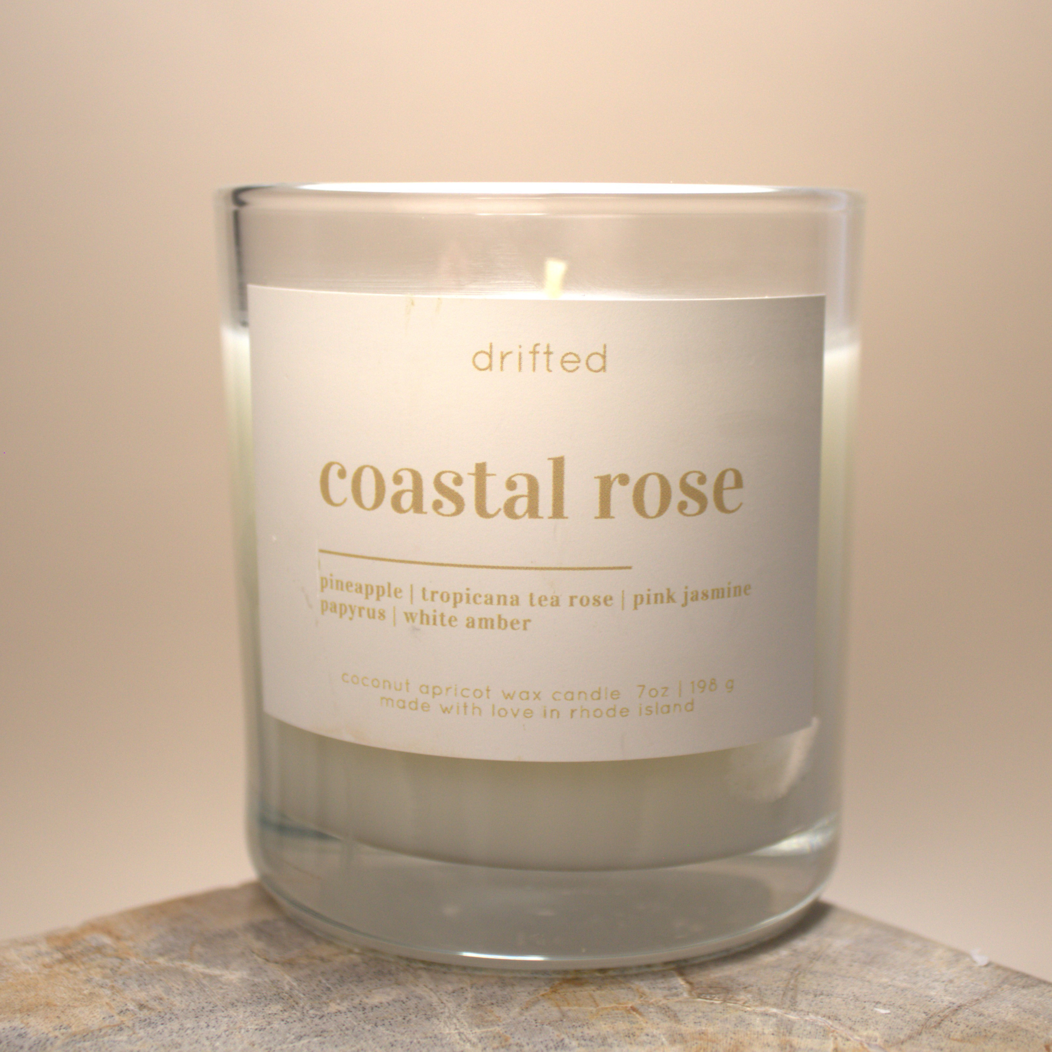 Candle labeled 'coastal rose' with a beige background