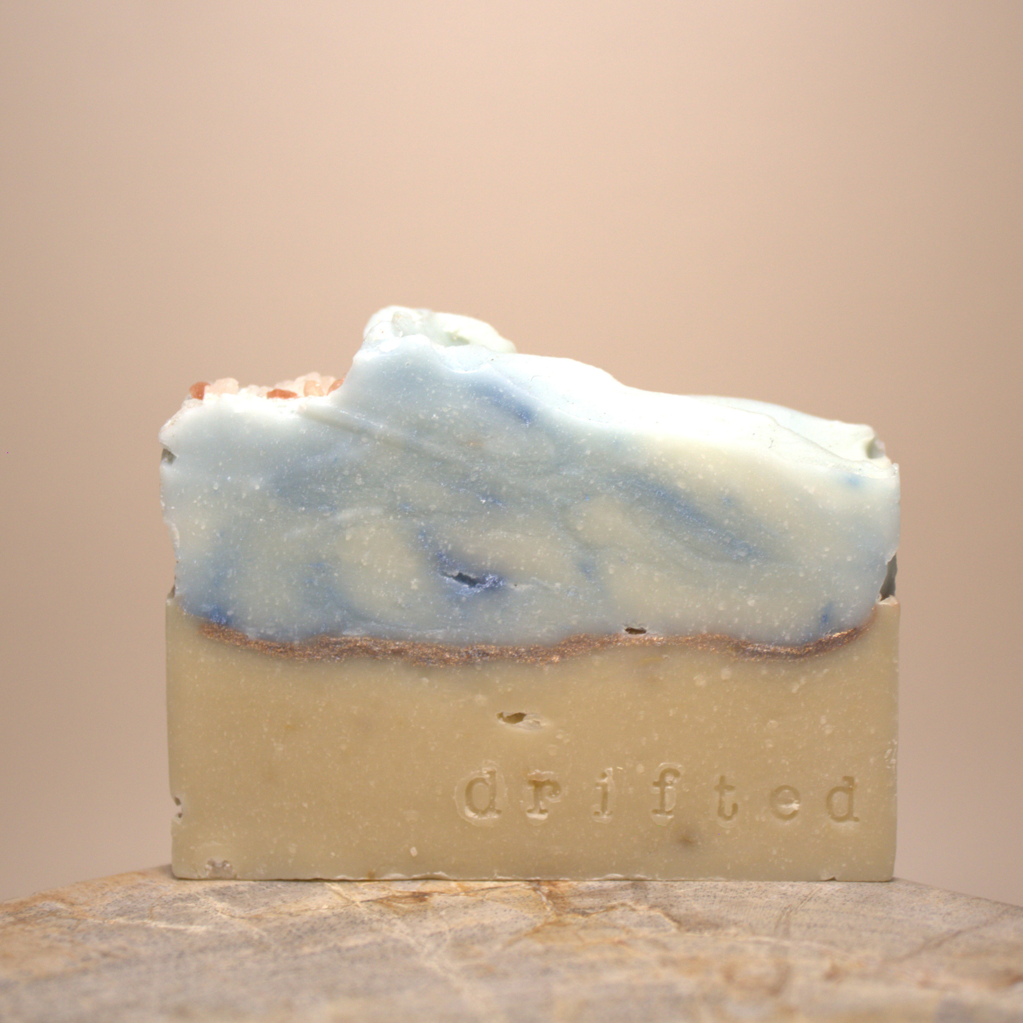 Bar of soap with blue and white swirls on a beige background, branded 'drifted'.