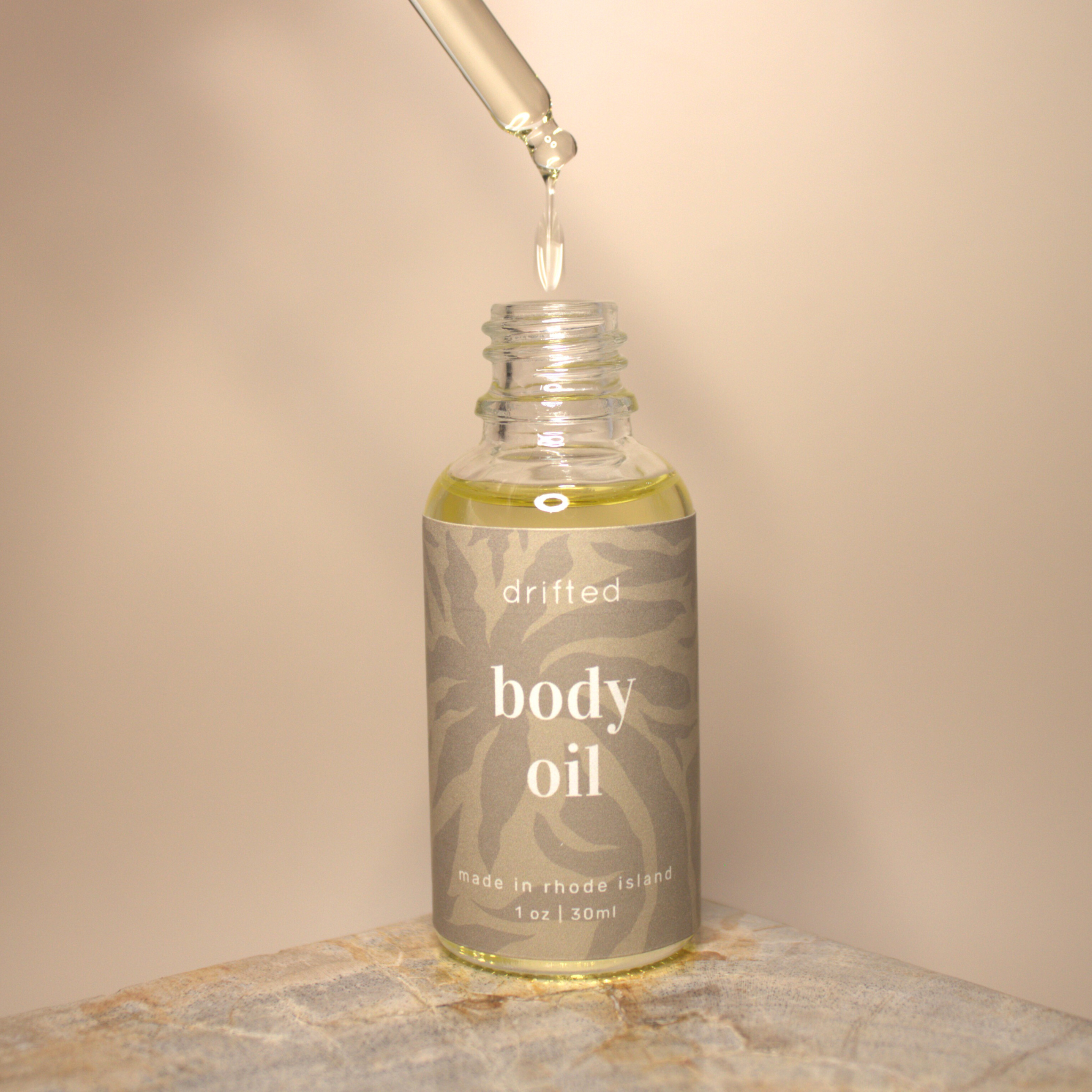 Bottle of body oil with dropper on a neutral background