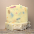 Two bars of soap with colorful specks on a neutral background