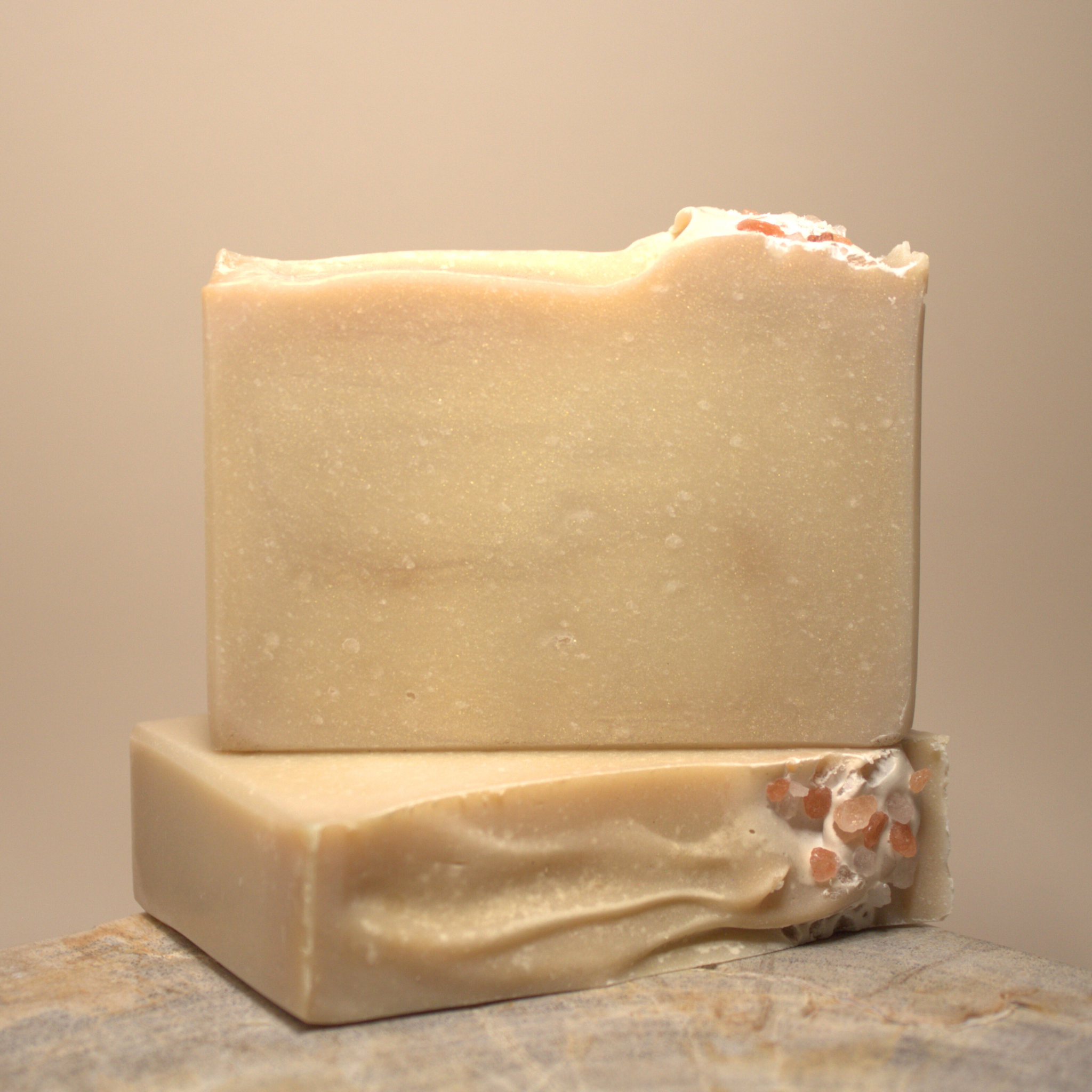 Two bars of soap on a textured surface with a neutral background